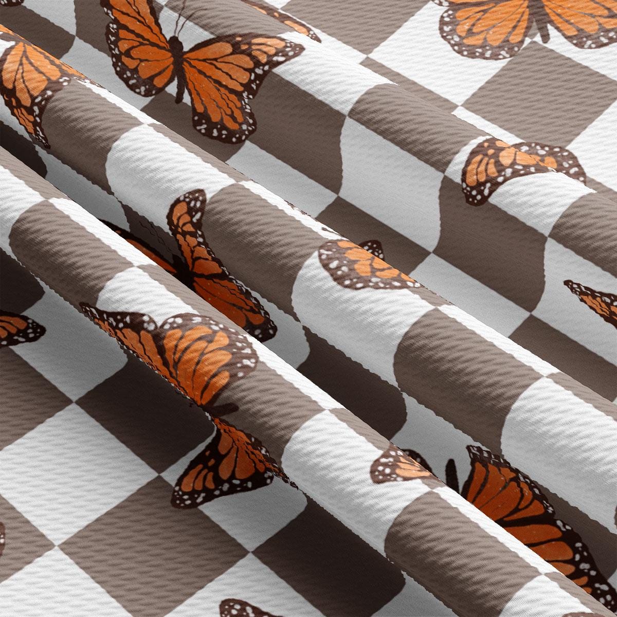 a close up of a checkered table cloth with orange butterflies on it