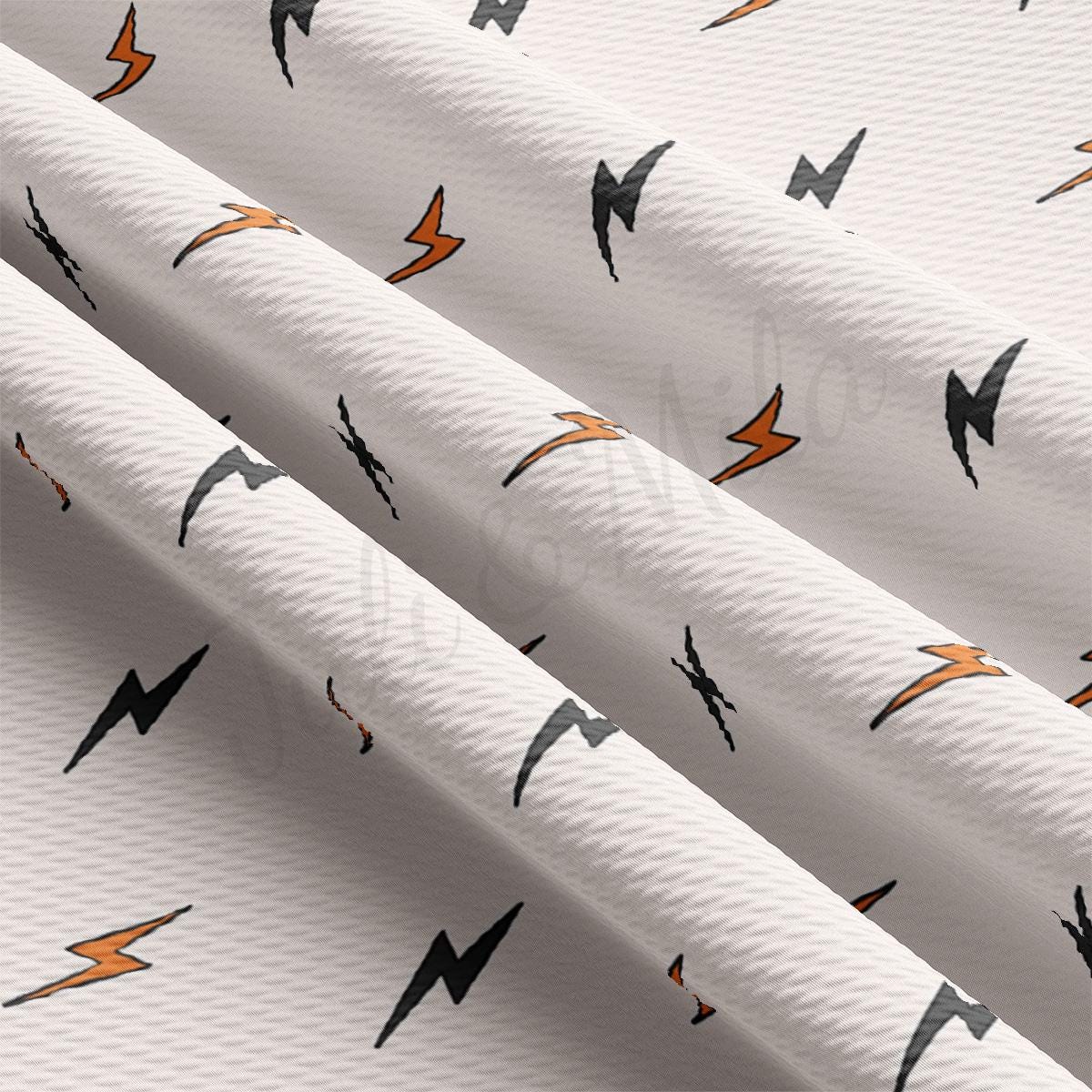 a close up of a pattern of white fabric with orange and black lightning bolts