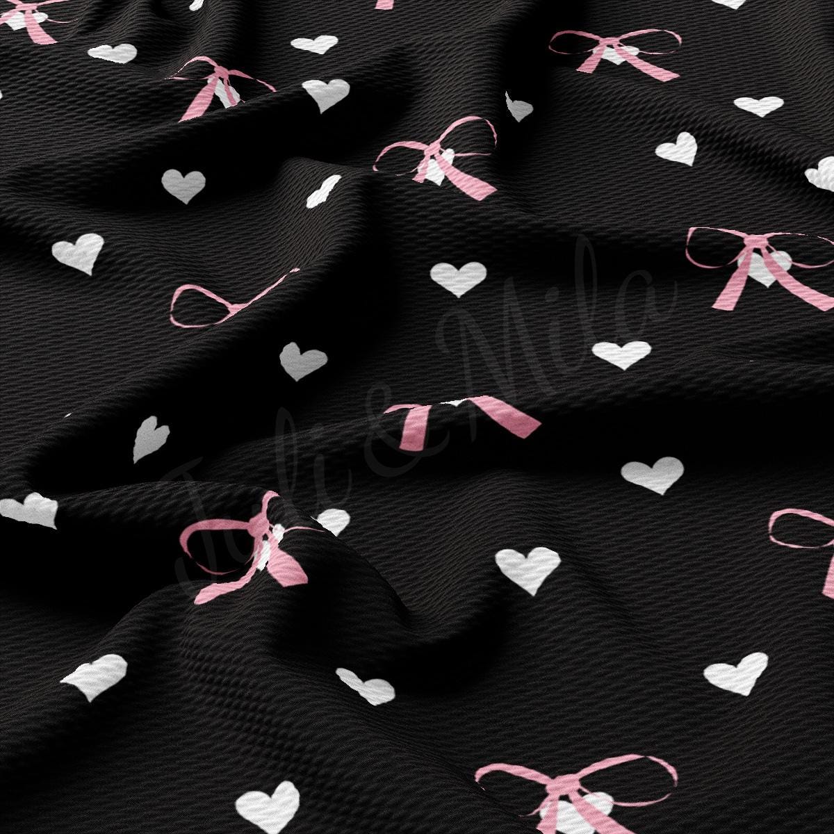 a black fabric with hearts and bows on it