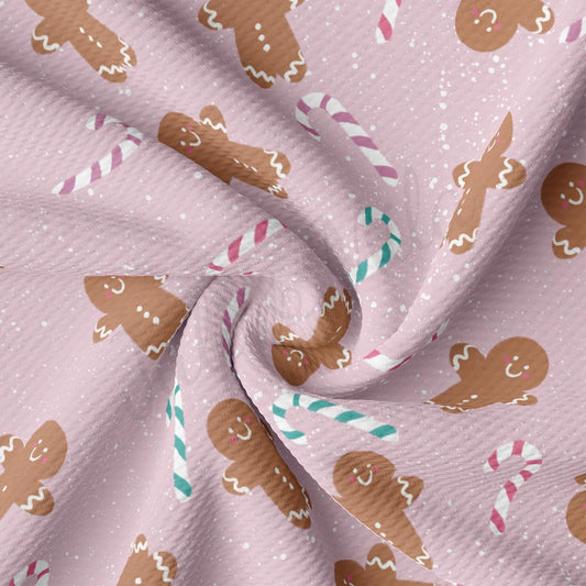 a pink fabric with gingerbreads and candy canes on it